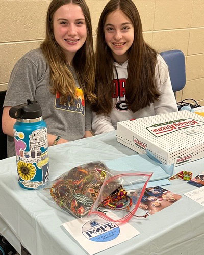 Two students sitting behind a table smiling